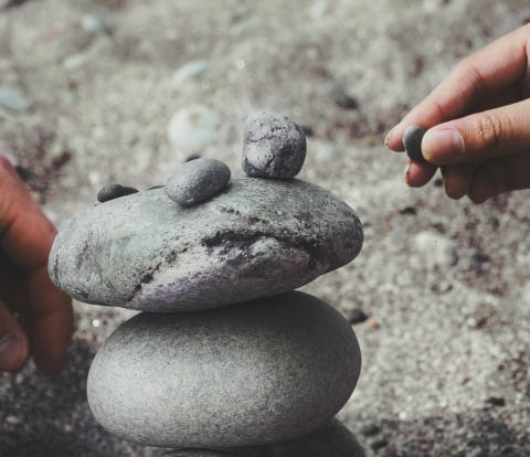 Image of two people balancing pebbles in a stack