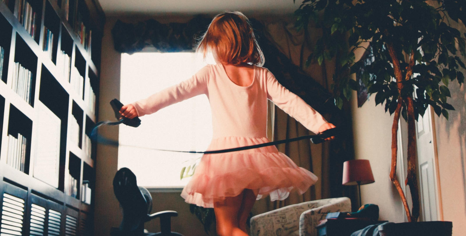Image of young girl in pink dress skipping through her apartment